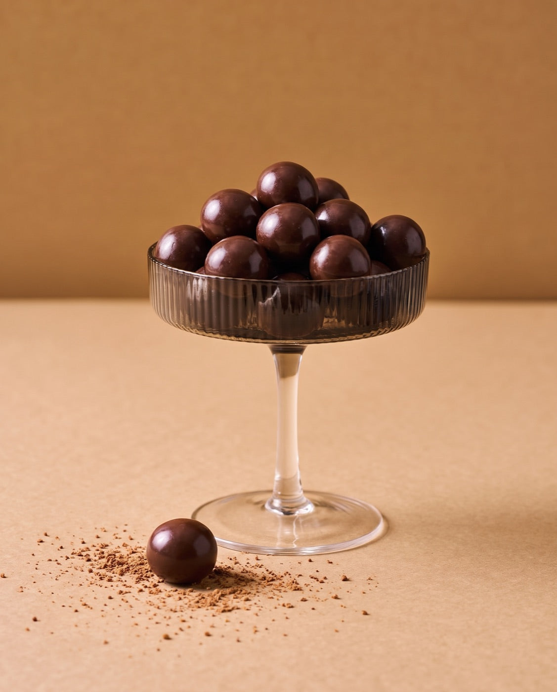 Chocolate coated cherries piled in a ribbed coupe glass.